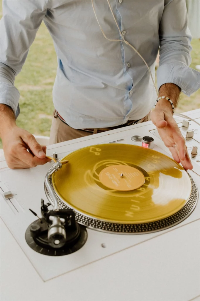Mains du DJ sur la table de mixage Pioneer gérant l'ambiance sonore pendant une soirée dansante au Domaine de Sarson